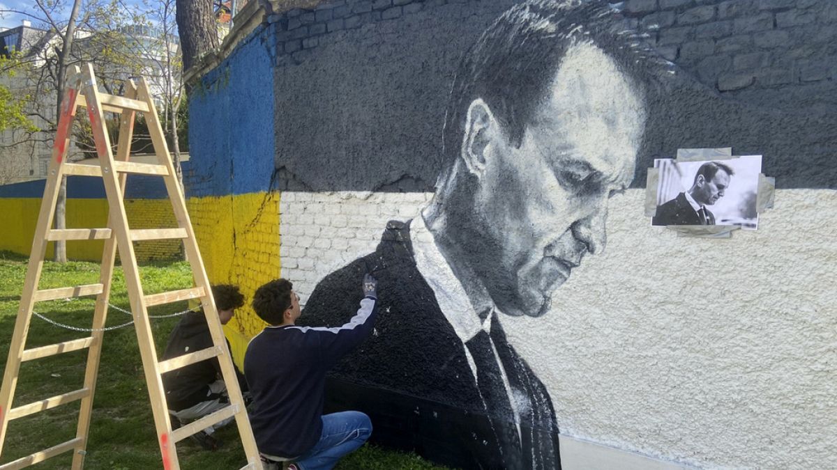 Artists spray-paint portraits of Alexei Navalny behind a Soviet monument in Vienna